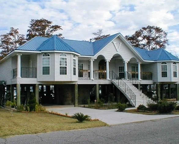 Elevated home with blue roof and wraparound covered porch