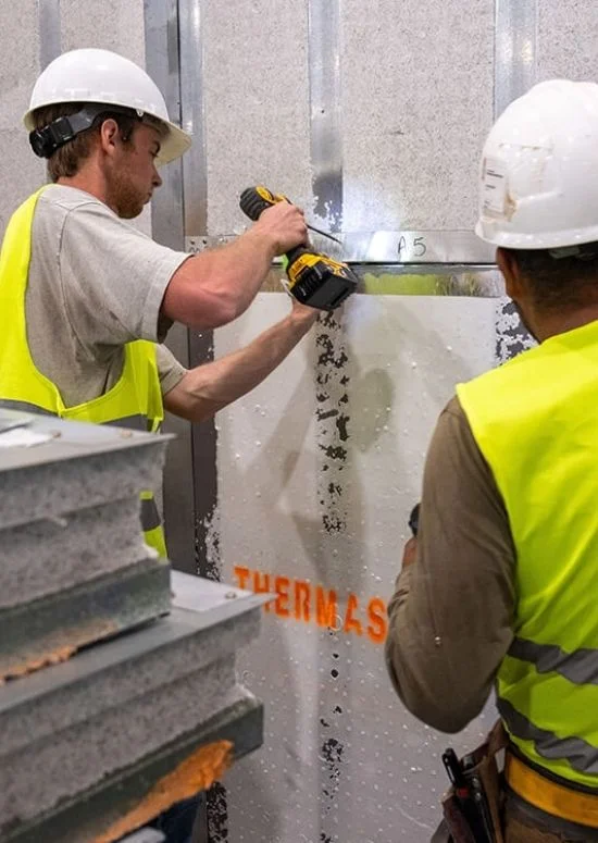 Workers installing branded ThermaSteel insulated panel on site