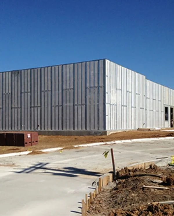 Two-story panel structure under construction on wooded lot