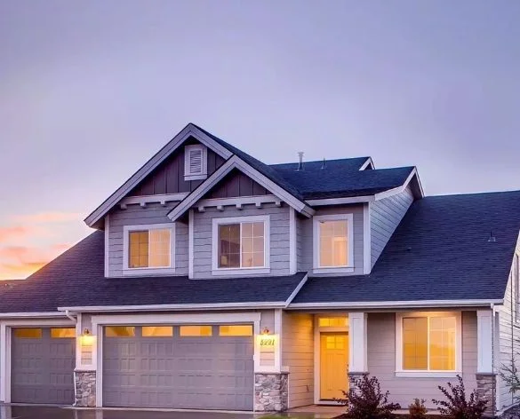 Two-story craftsman home with stone accents lit at dusk