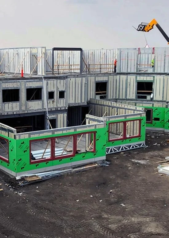 Multi-unit panel structure under construction with green weather barrier